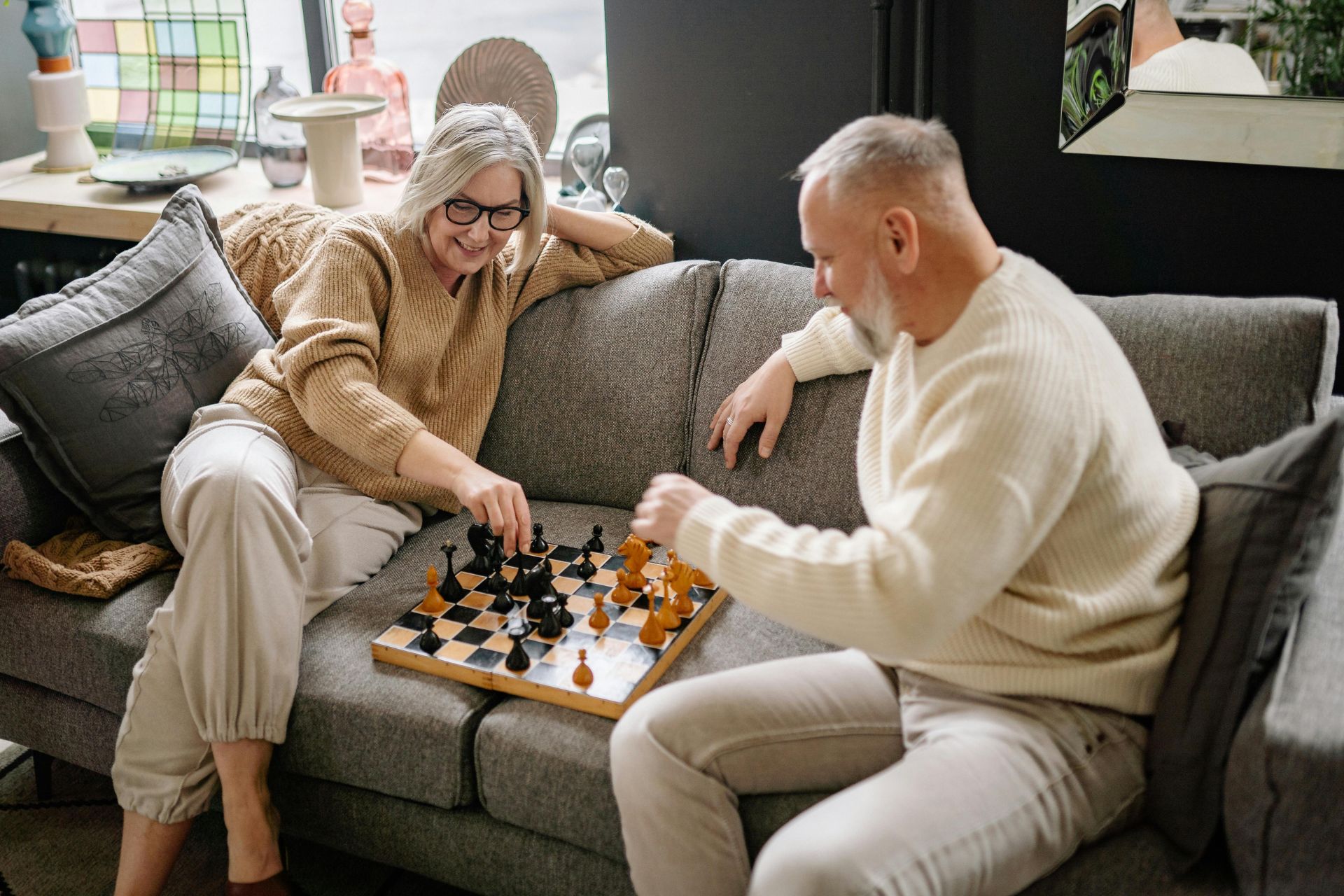Happy retired couple playing chess while thoughtfully strategizing the best age to start Social Security benefits.