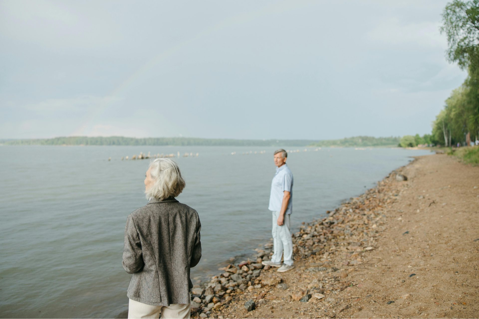 Retired couple standing on a lake's shoreline.